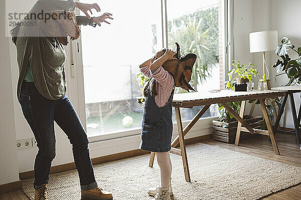 Grandmother and granddaughter wearing animal masks playing together at home