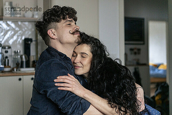 Man embracing girlfriend in kitchen at home