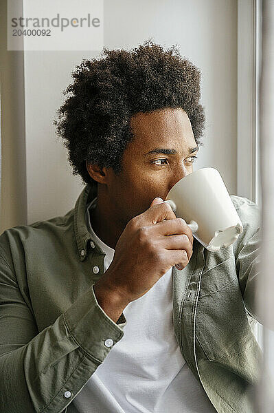 Man drinking from coffee cup at home