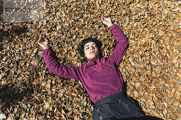 Carefree woman lying down on autumn leaves