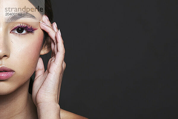 Beautiful young woman with make-up against grey background