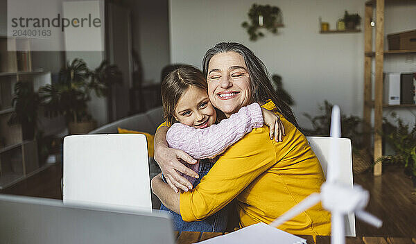 Smiling grandmother and granddaughter hugging each other at home