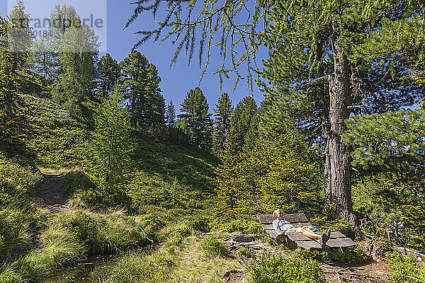 Austria  Salzburger Land  Female hiker relaxing on mountain bench in summer