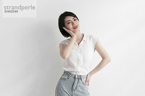 Smiling woman standing with hand on hip against white background