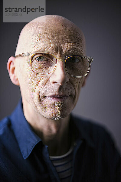 Elderly man with eyeglasses against black background