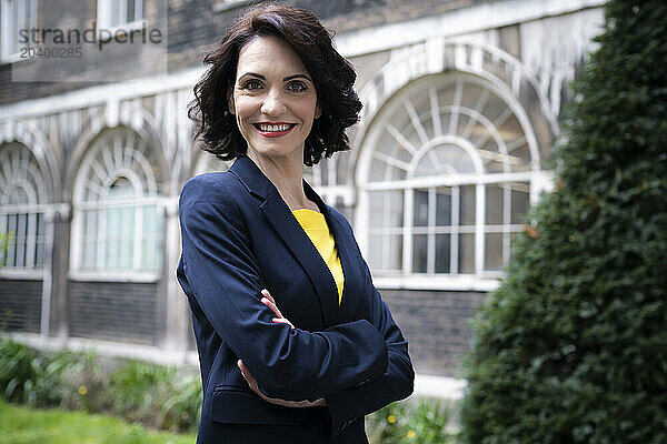 Confident businesswoman standing with arms crossed at office park