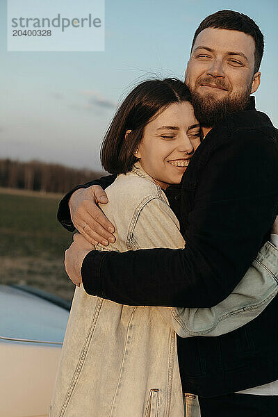 Smiling couple embracing each other at sunset