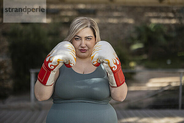 Curvy woman wearing boxing gloves in park