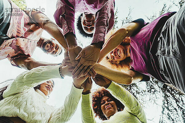 Multiracial friends stacking hands at park