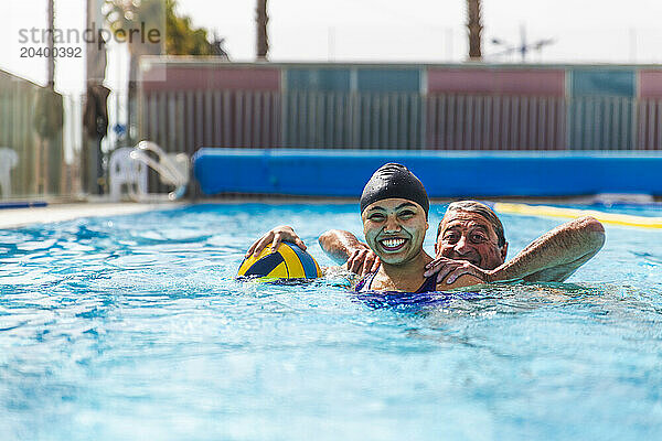 Playful senior man and young woman enjoying together in swimming pool