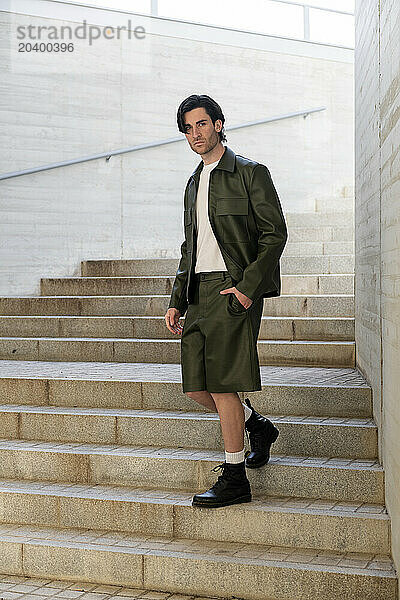 Handsome young fashionable man moving down on steps