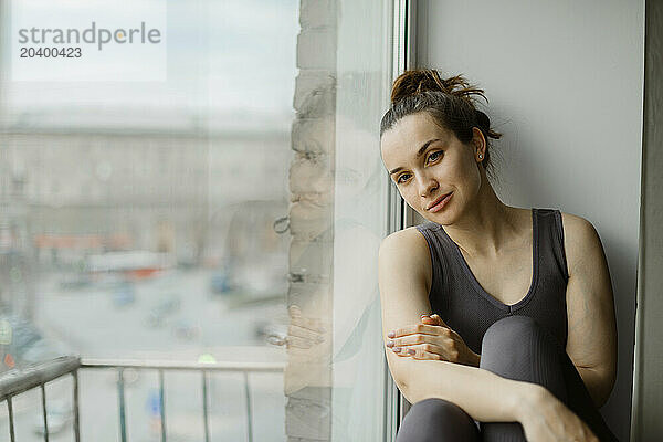 Woman leaning on glass window at home