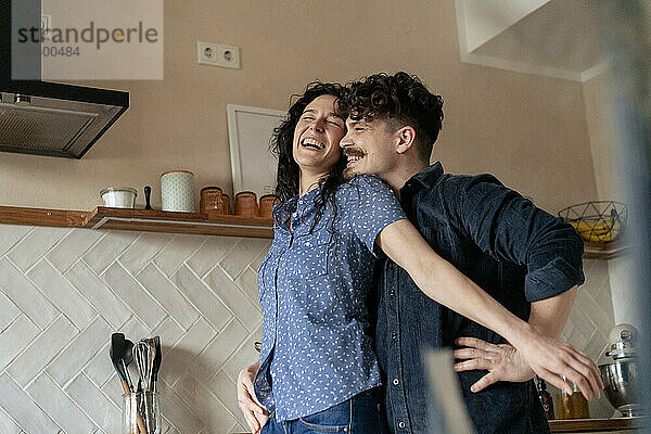 Happy couple spending leisure time in kitchen at home