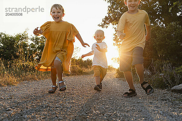 Happy siblings running on footpath at sunset