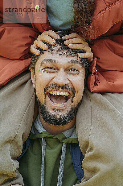 Happy man laughing with woman sitting on shoulder