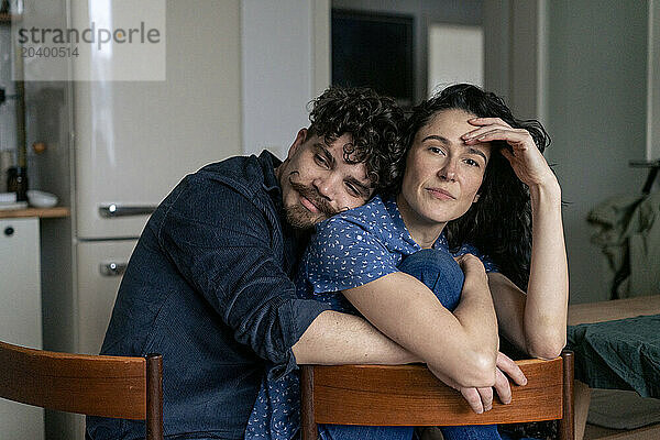 Couple sitting together on chairs at home