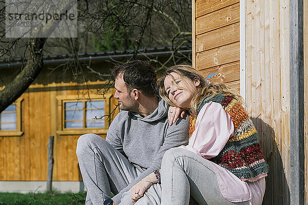 Smiling couple sitting together in back yard on sunny day