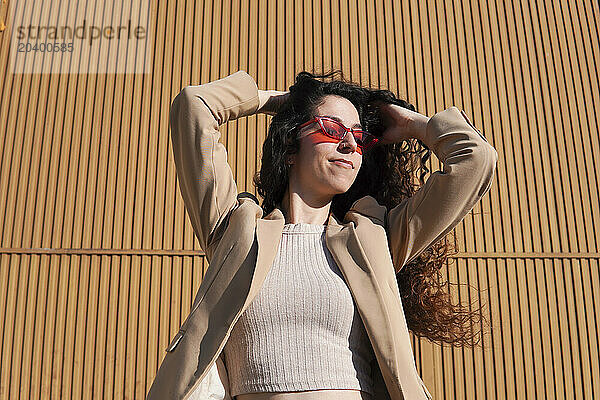 Woman with curly hair wearing red sunglasses on sunny day