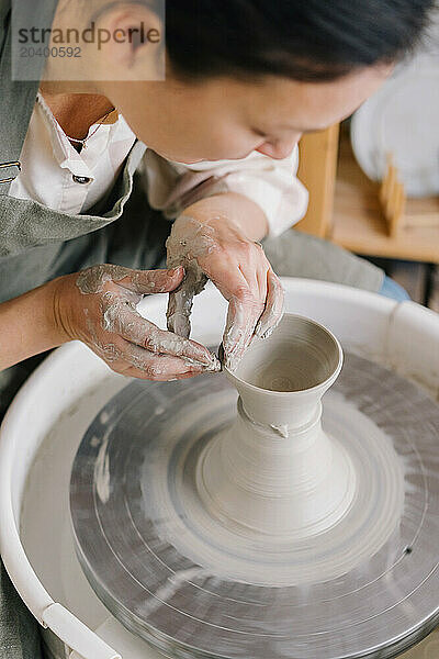 Confident artist molding clay on pottery wheel at art studio