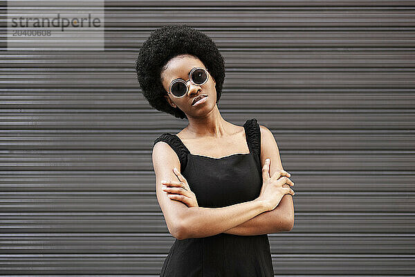 Confident woman standing with arms crossed in front of shutter