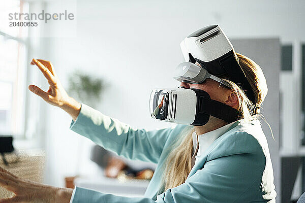 Businesswoman wearing virtual reality headsets gesturing at office