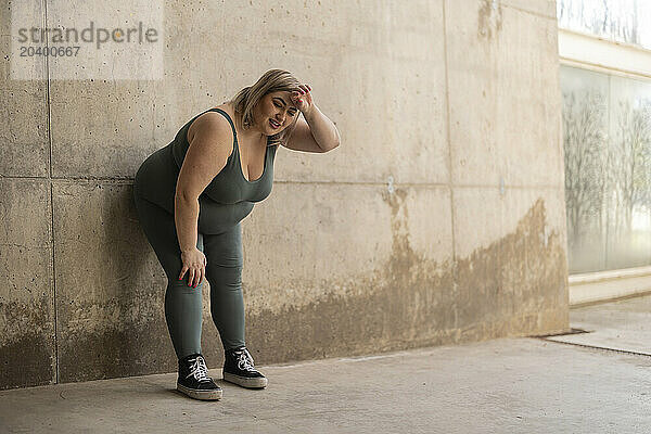 Tired curvy woman leaning on wall