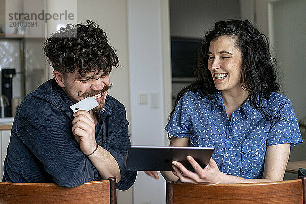 Happy couple doing online shopping through tablet PC at home