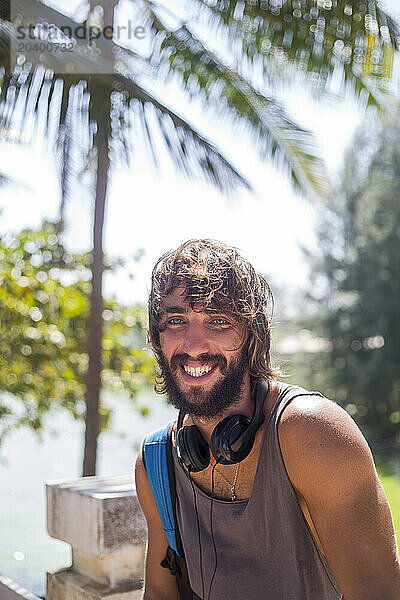 Smiling bearded man with headphones on sunny day