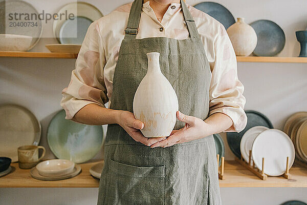 Potter standing with ceramic vase at workplace