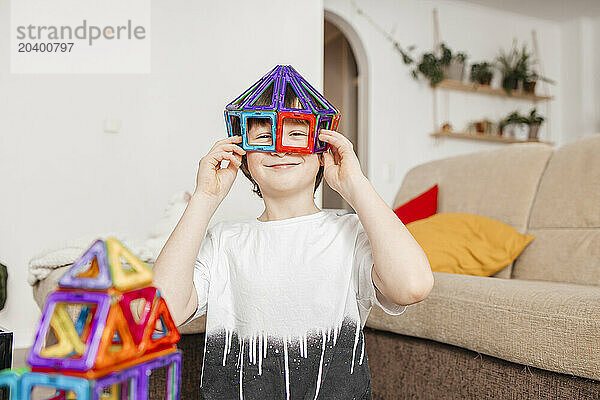 Smiling boy playing with construction kit at home