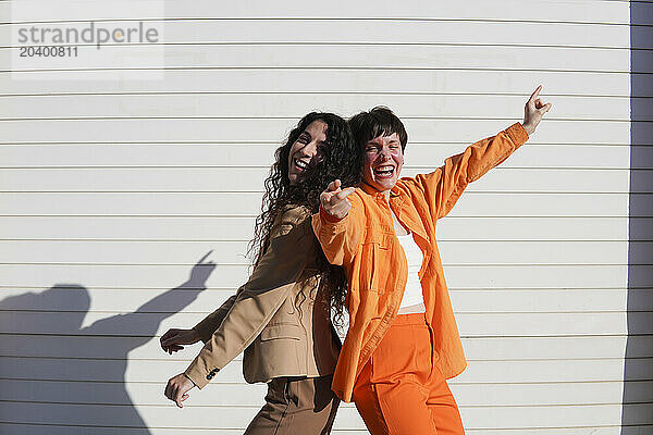 Happy gay couple dancing together in front of white wall