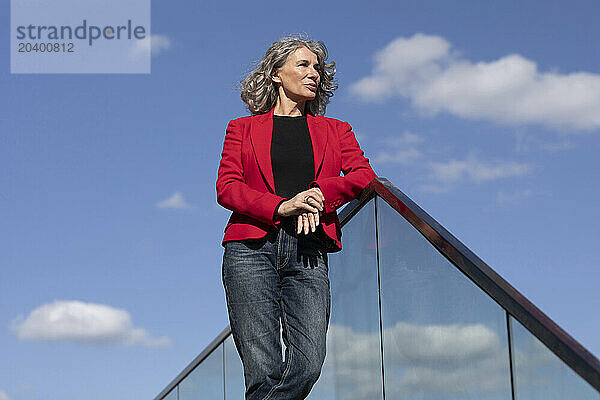 Businesswoman standing near railing under sky