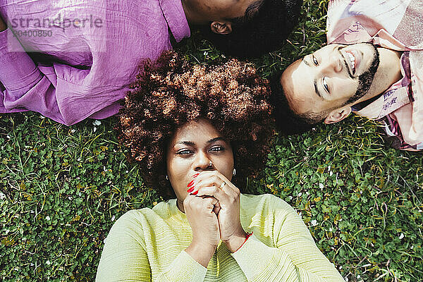 Afro woman lying down on grass with friends at park