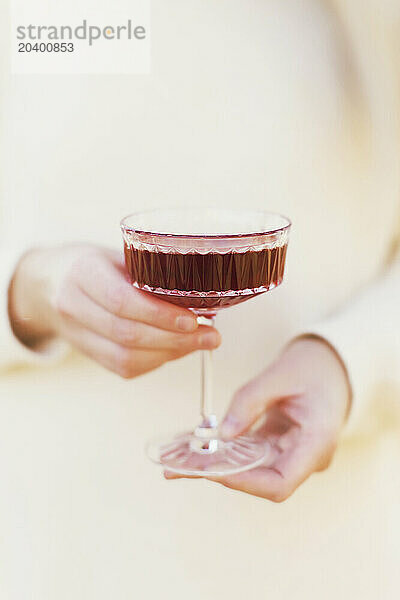 Woman holding glass of red wine in forest