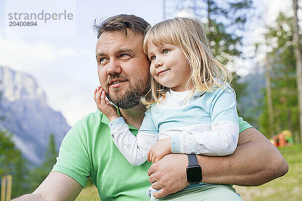 Father with blond daughter looking away