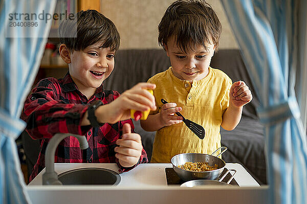 Siblings playing with toy kitchen at home