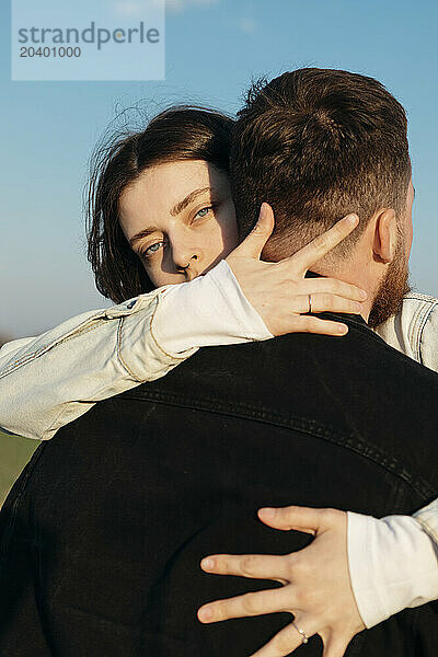 Young woman embracing boyfriend on sunny day