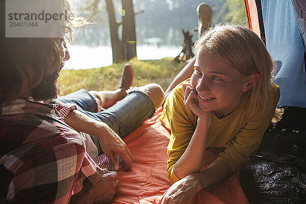 Smiling woman lying next to boyfriend in tent