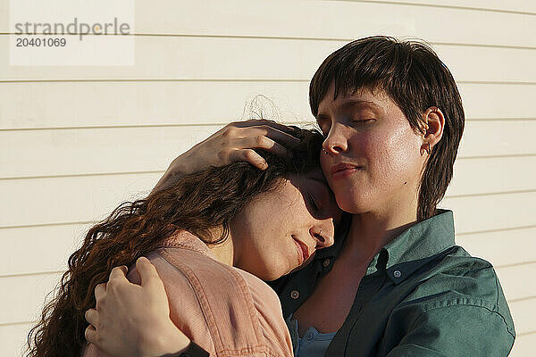 Lesbian couple embracing each other on sunny day