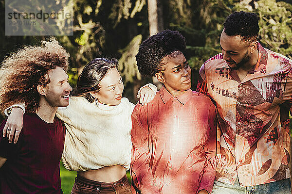 Multiracial friends walking with arm around at park