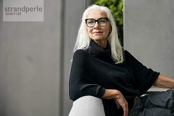 Smiling woman with eyeglasses sitting at home