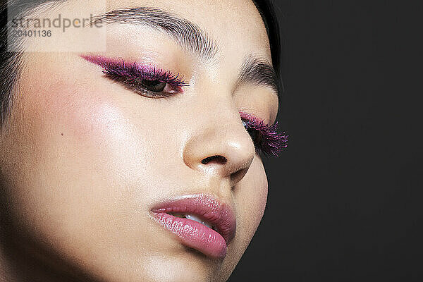 Beautiful young woman with make-up over grey background