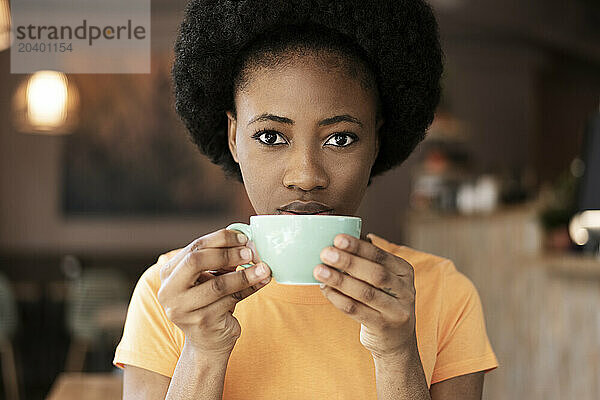 Young Afro woman drinking coffee at cafe