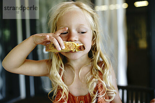 Blond girl eating breakfast at home