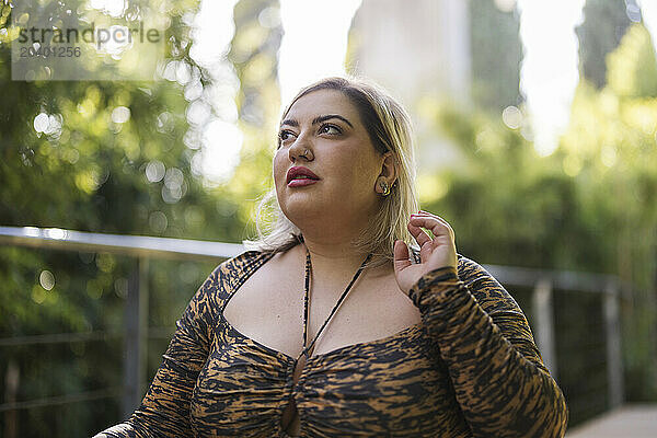 Young curvy woman wearing leopard print top in park