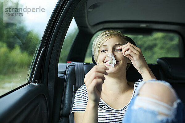 Smiling young woman eating bubble gum sitting in car