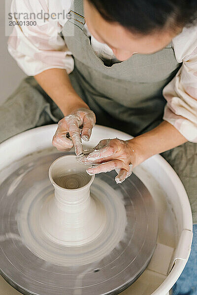 Potter molding clay on pottery wheel at art studio