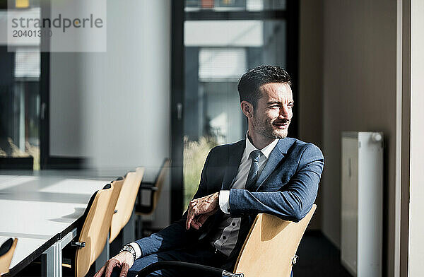 Smiling mature businessman sitting on chair at office