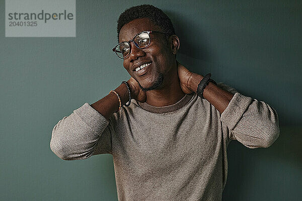 Smiling young man in front of green wall