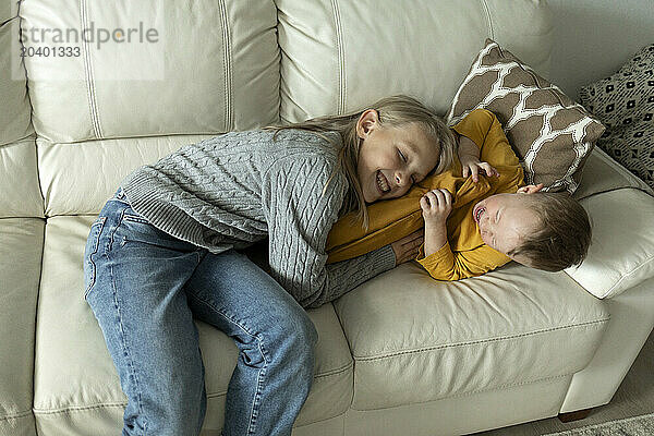 Brother and sister playing on sofa at home